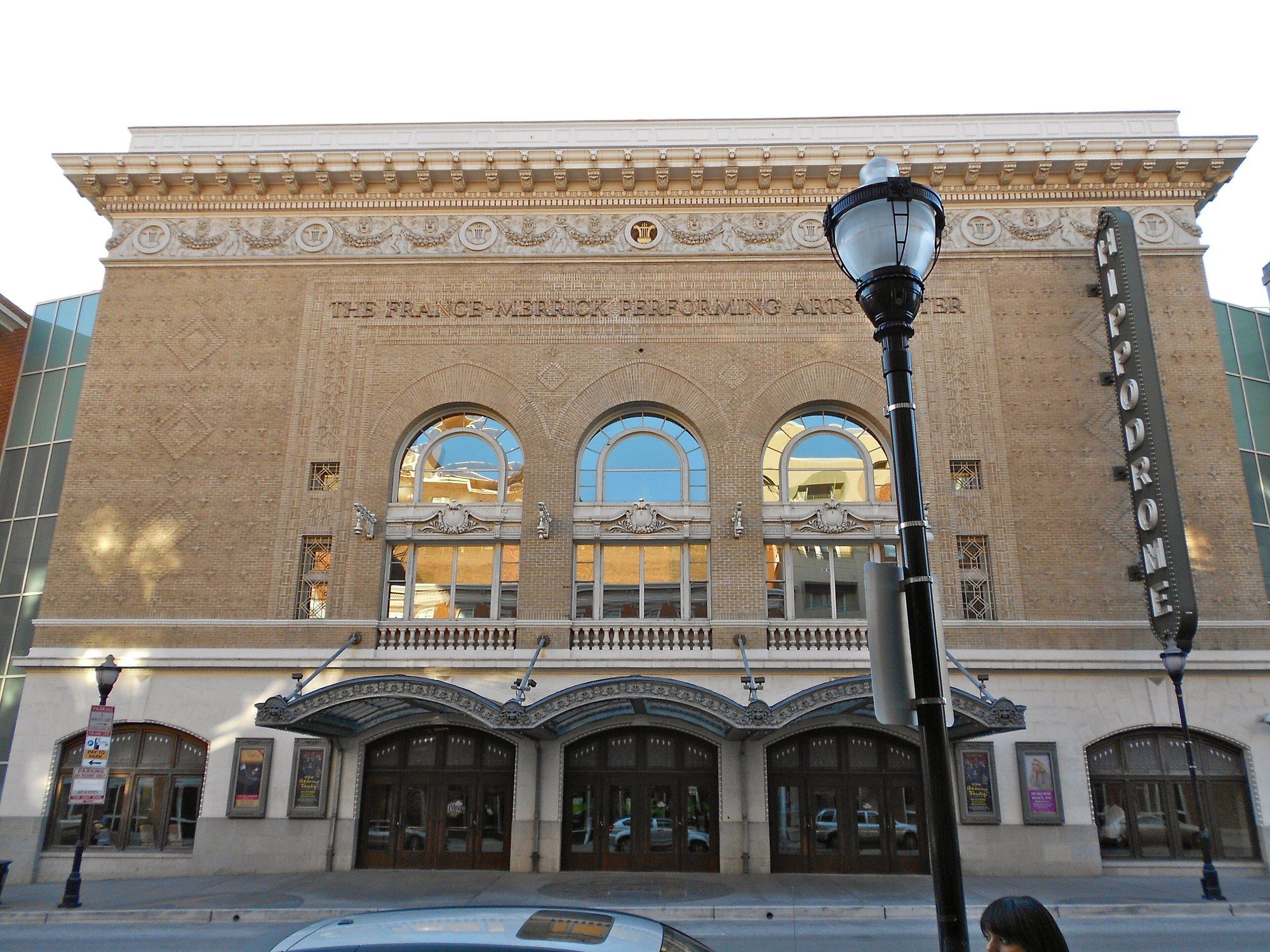 The Hippodrome Theatre on Eutaw Street in Baltimore: a tan brick facade with three arched windows, a vertical “Hippodrome” sign and an iron canopy over the doors