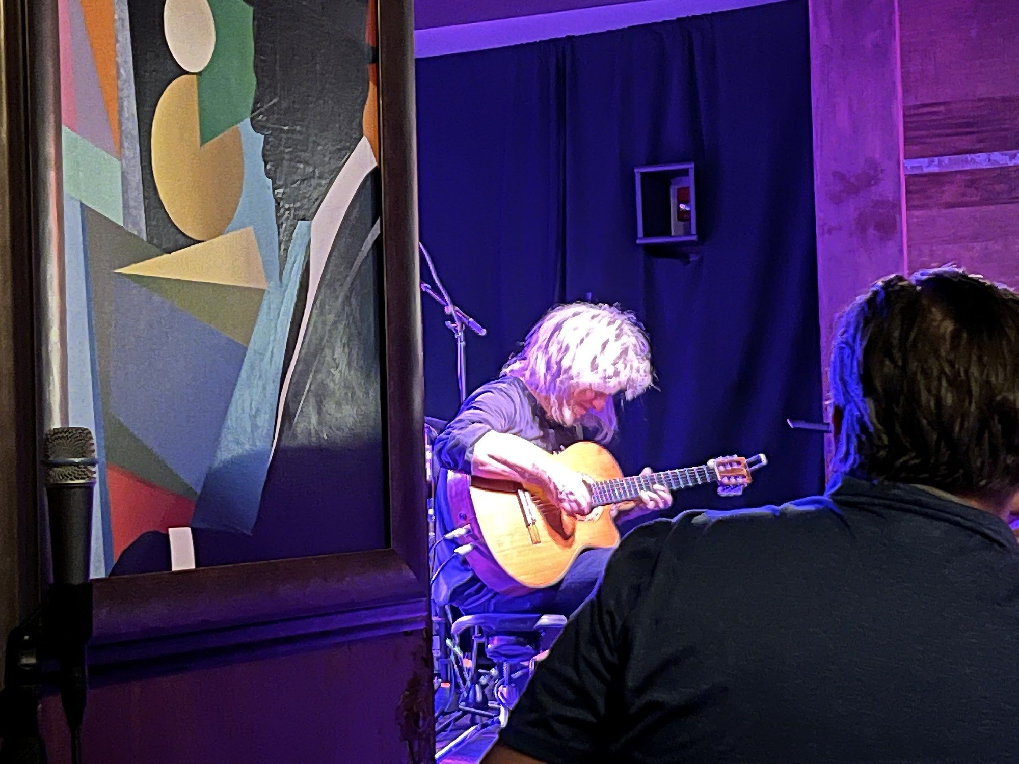 Pat Metheny seated under purple light playing a nylon-string acoustic guitar at Keystone Korner