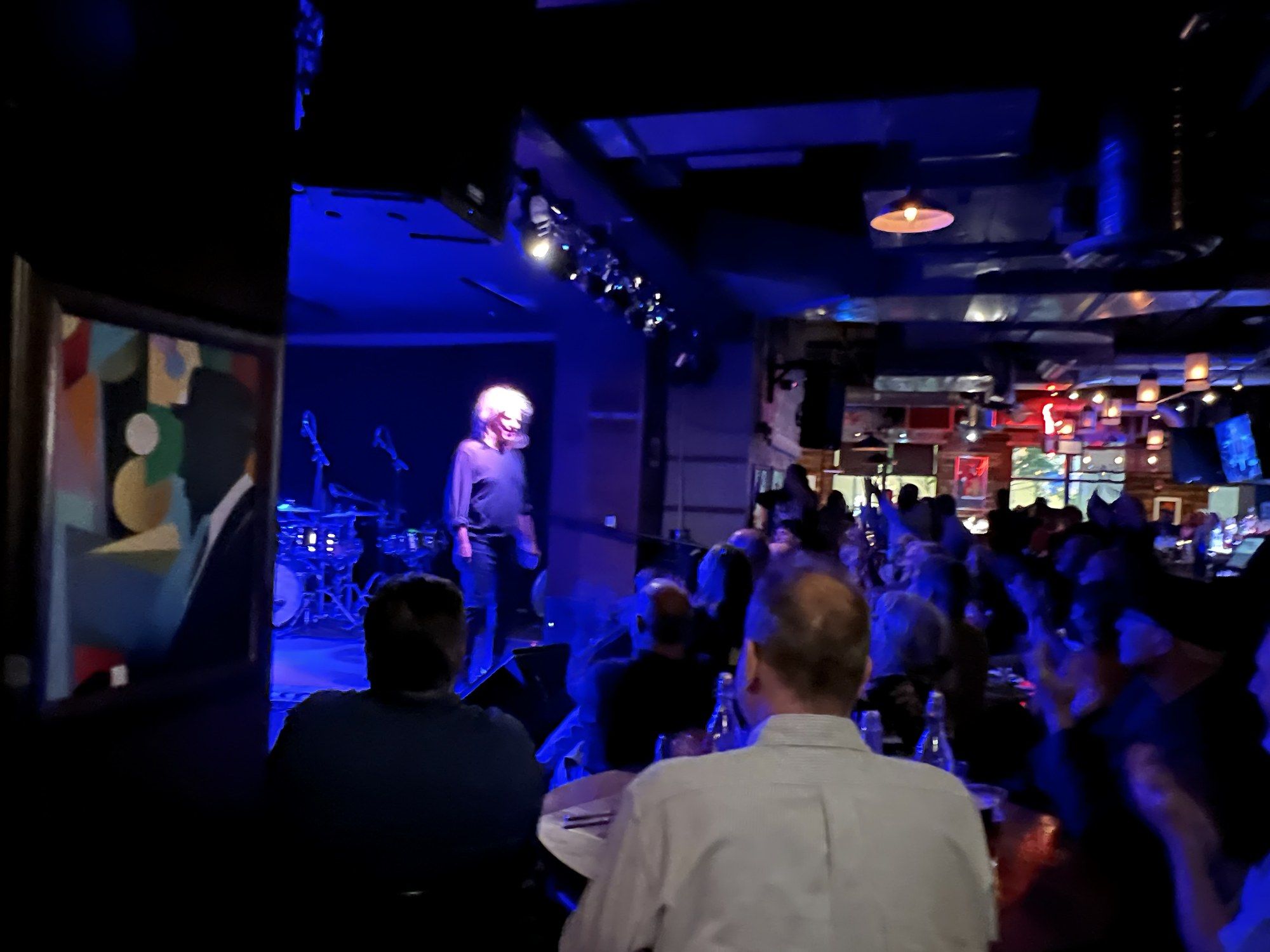 Blue-lit club interior at Keystone Korner with Pat Metheny standing at the stage as the audience applauds
