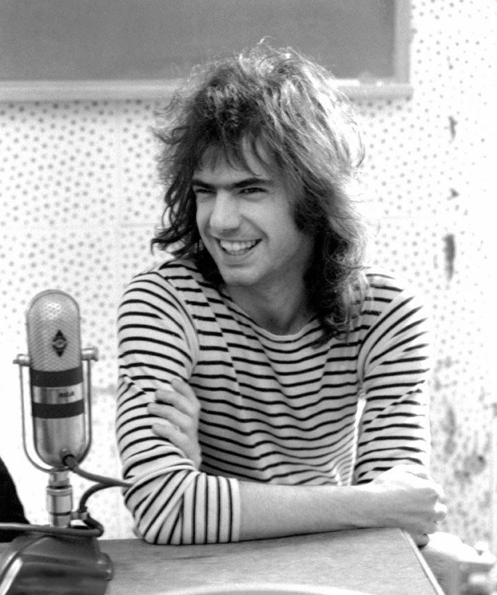 Black-and-white photo of a young Pat Metheny, smiling, seated at a radio studio microphone