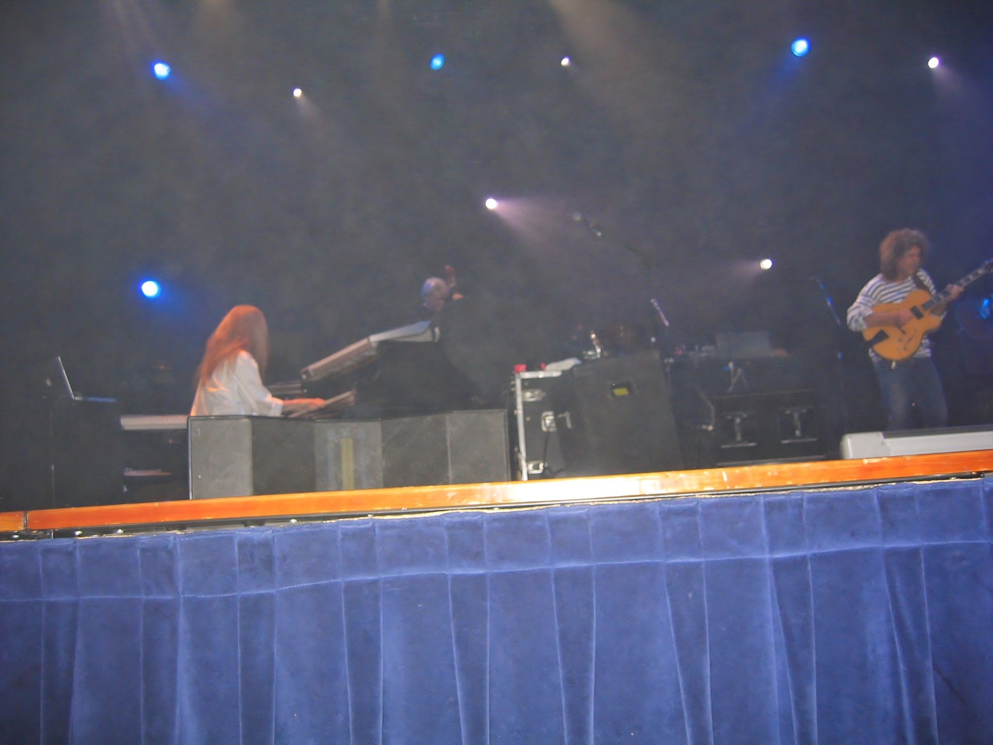 Blue-lit stage with a keyboardist on the left and Pat Metheny playing a hollow-body guitar on the right